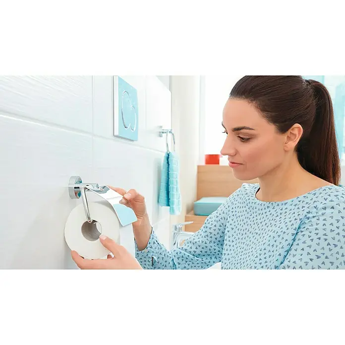 Tesa Smooz Toilettenpapierhalter - Mit Deckel, Chrom, Glänzend - Frau im Badezimmer wechselt Toilettenpapier. Der Halter ist aus Chrom mit einem eleganten, modernen Design, das das Badezimmer aufwertet.