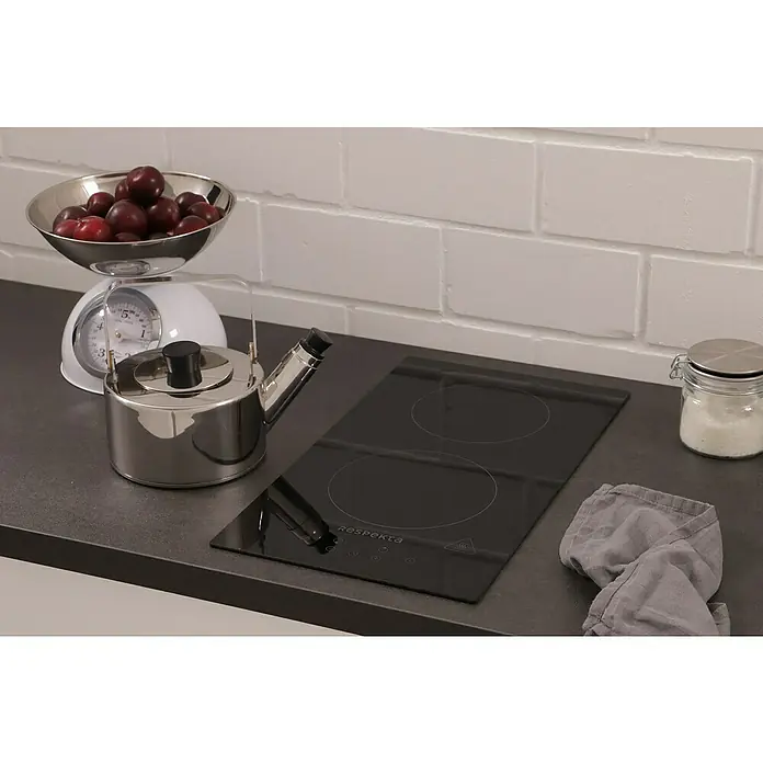 Respekta Kochfeld Ben - Anzahl Normalkochstellen: 2 Stk. - Detailaufnahme eines Respekta-Kochfelds auf einer Küchentheke mit einem Wasserkocher, einer Waage mit Pflaumen und einem Glas mit Inhalt.