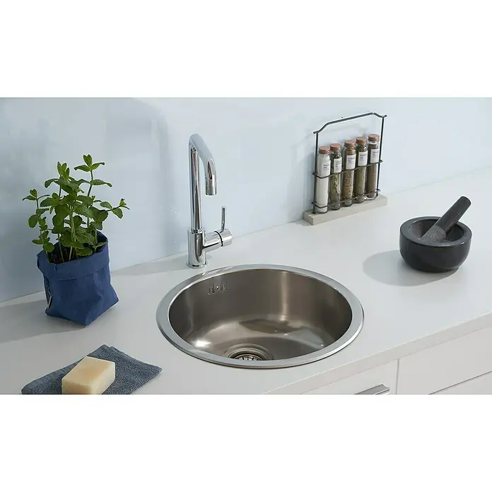 Respekta Einbauspüle Portland - Durchmesser: 44,6 cm, Edelstahl - Eine moderne Küchenspüle mit einem runden Edelstahlbecken, einer Armatur, Kräutern, Mörser und Seife auf einer weißen Arbeitsfläche.