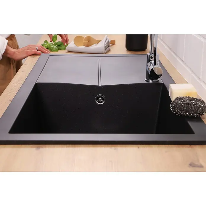 Respekta Einbauspüle Cleveland - 100 x 50 cm, Schwarz - Nahaufnahme einer modernen, schwarzen Küchenspüle mit Arbeitsfläche. Ein Wasserhahn, Seife und ein Spülschwamm stehen bereit für den Abwasch.