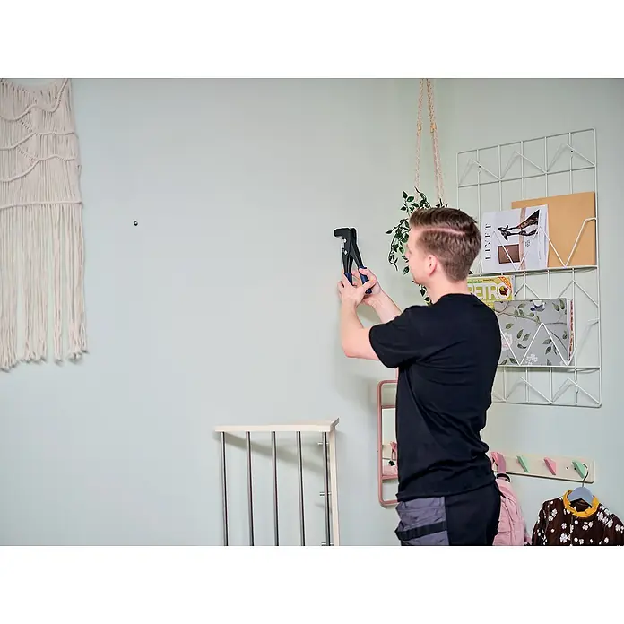 Rapid Montagezange - Für Schrauben M4, M5 und M6 in Hohlraumdübeln - Mann befestigt mit einer Nietenzange ein Regal an der Wand. Ein praktisches Werkzeug für die Heimwerkerarbeit.