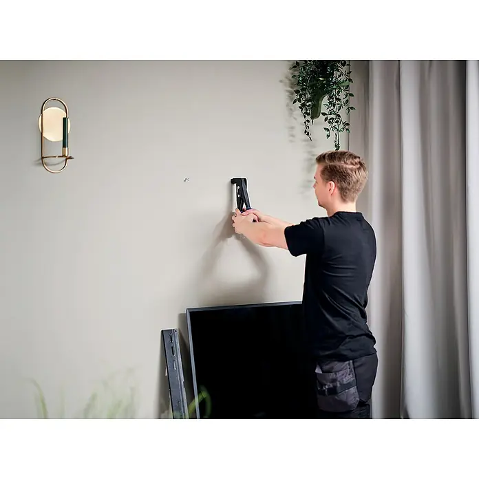 Rapid Montagezange - Für Schrauben M4, M5 und M6 in Hohlraumdübeln - Ein Mann befestigt eine TV-Halterung an einer Wand. Eine moderne Wandlampe und ein Fernseher sind ebenfalls im Bild zu sehen.