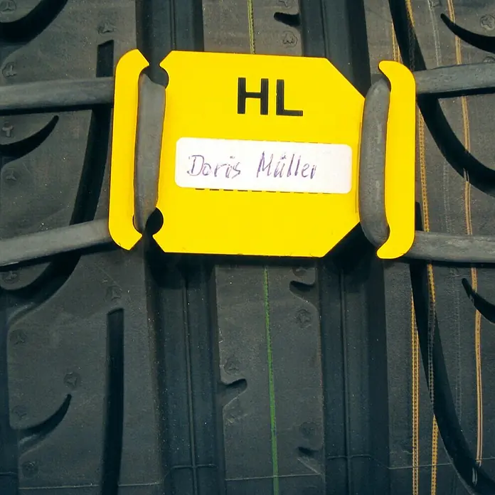 Scholz Markierungsschilder-Set Rad-Mark ZIB - 4 Stk. - Nahaufnahme eines Reifens mit gelbem Etikett mit der Aufschrift "HL Doris Müller", das an den Reifen gebunden ist.