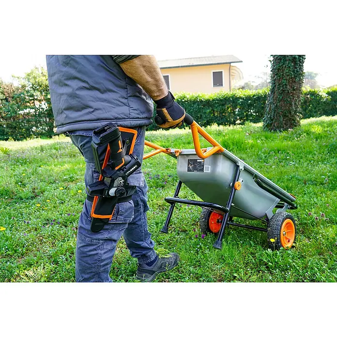 Worx PowerShare 20V Sierra de ramas de batería WG325E.9 - 20 V, Iones de litio, Sin batería, Longitud de la cuchilla: 12 cm - Una persona empuja una carretilla WORX gris con detalles naranjas por un césped.