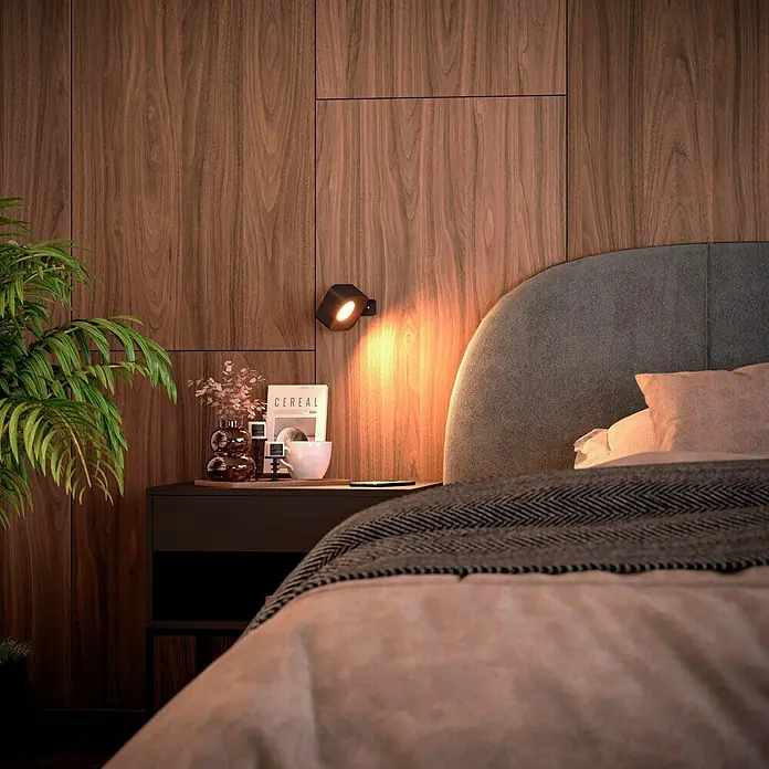 Lavida Akku-Wandleuchte Mirano - L x B x H: 9,25 x 7,65 x 4,5 cm, 2 W, Schwarz, Mehrfarbig, Eckig - Ein Schlafzimmer mit einem Nachttisch, auf dem eine Lampe, eine Vase und ein Buch stehen. Das Bett ist mit einer Decke bedeckt.