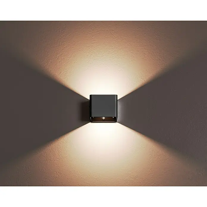 Lavida Akku-Wandleuchte Lucca - L x B x H: 10 x 10 x 8 cm, 1,2 W, Schwarz, Warmweiß - Das Bild zeigt eine moderne, graue Wandleuchte, die ein warmes, stimmungsvolles Licht nach oben und unten wirft.