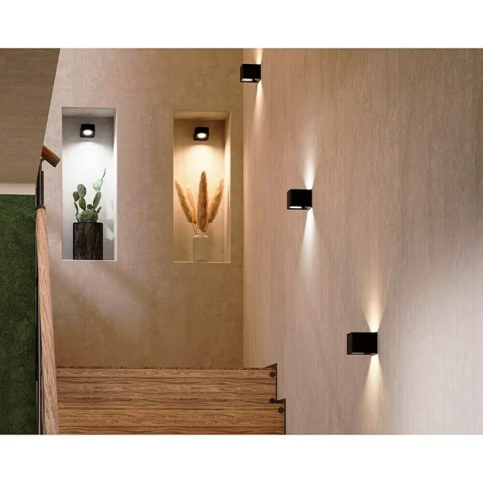 Lavida Akku-Wandleuchte Mirano - L x B x H: 9,25 x 7,65 x 4,5 cm, 2 W, Schwarz, Mehrfarbig, Eckig - Wandleuchten aus würfelförmigem, schwarzem Metall erhellen einen stilvollen Flur mit Nischen, die mit Pflanzen und Kunst dekoriert sind.