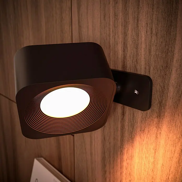 Lavida Akku-Wandleuchte Mirano - L x B x H: 9,25 x 7,65 x 4,5 cm, 2 W, Schwarz, Mehrfarbig, Eckig - Nahaufnahme einer modernen, schwarzen Wandleuchte mit warmweißem Licht an einer Holzvertäfelung.