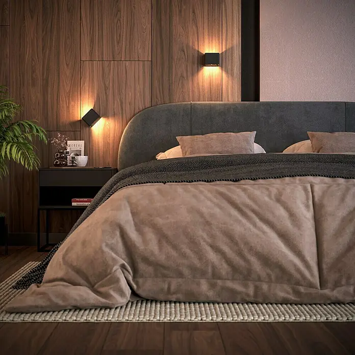Lavida Akku-Wandleuchte Lucca - L x B x H: 10 x 10 x 8 cm, 1,2 W, Schwarz, Warmweiß - Nahaufnahme eines Bettes mit gepolstertem Kopfteil, Nachttischlampe und Nachttisch mit Dekor vor einer Holzwand.