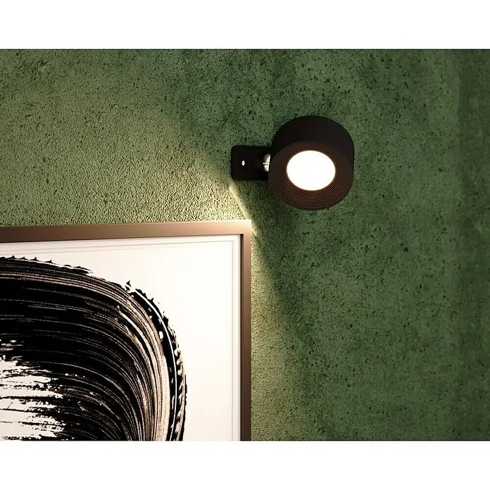 Lavida Akku-Wandleuchte Novara - L x B x H: 9,25 x 7,6 x 4,5 cm, 2 W, Schwarz, Mehrfarbig, Rund - Nahaufnahme einer modernen schwarzen Wandleuchte, die ein Kunstwerk stilvoll beleuchtet, mit Fokus auf das Lichtdesign und die grüne Wandtextur.