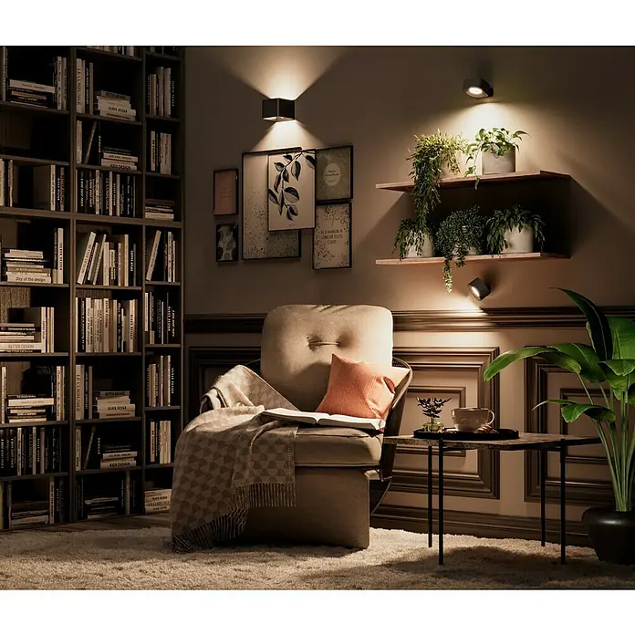 Lavida Akku-Wandleuchte Mirano - L x B x H: 9,25 x 7,65 x 4,5 cm, 2 W, Schwarz, Mehrfarbig, Eckig - Gemütliches Wohnzimmer mit Bücherregal, Sessel, Beistelltisch und Zimmerpflanzen unter warmem Licht.