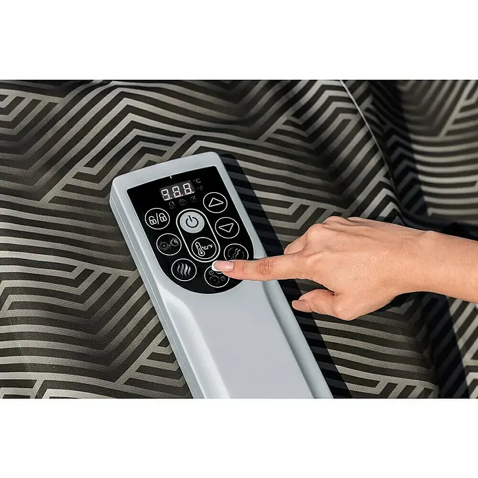 Bestway Lay-Z-Spa Mobil-Whirlpool Barbuda AirJet - Ø x H: 180 x 66 cm, Grau, 669 l - Nahaufnahme einer Hand, die die Steuerung einer Heizmatte bedient, die auf einer gemusterten Oberfläche liegt. Die Steuerung zeigt Temperatur- und Funktionsoptionen an.