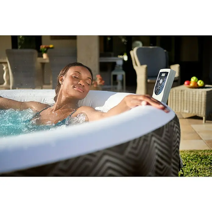Bestway Lay-Z-Spa Mobil-Whirlpool Barbuda AirJet - Ø x H: 180 x 66 cm, Grau, 669 l - Entspannen Sie im aufblasbaren Whirlpool. Die Frau genießt die Massage im Pool mit Bedienfeld und Obstschale in der Nähe.