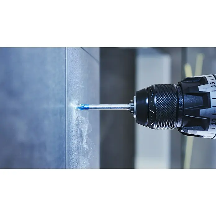 Bosch Professional Expert Bohrer-Set EXPERT HEX-9 HardCeramic5 Stk., Durchmesser Bohrer: 6 mm - Nahaufnahme eines Bohrers mit einem blauen Bohrer, der in eine graue Fliese bohrt, wobei Staub entsteht. Das Werkzeug ist gut fokussiert.