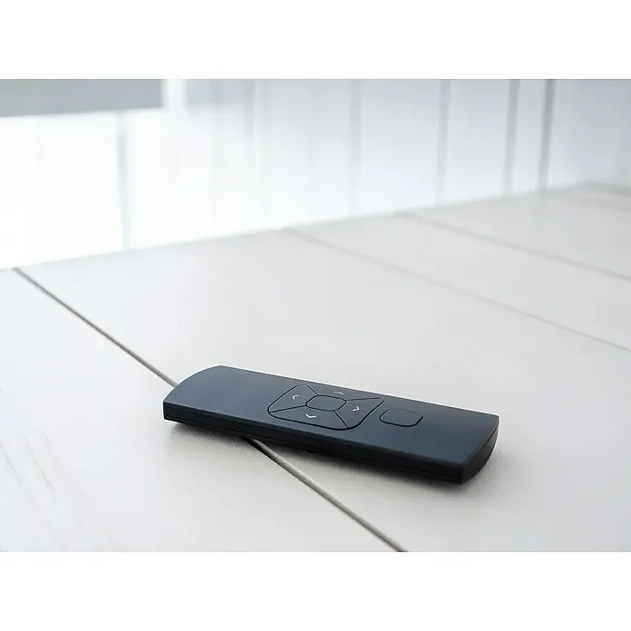Funkhandsender MotionBlinds Smart Home Remote Control - 5 Kanäle - Nahaufnahme einer schwarzen Fernbedienung auf einem weißen Tisch, vor einem hellen Hintergrund. Die Fernbedienung liegt im Fokus.