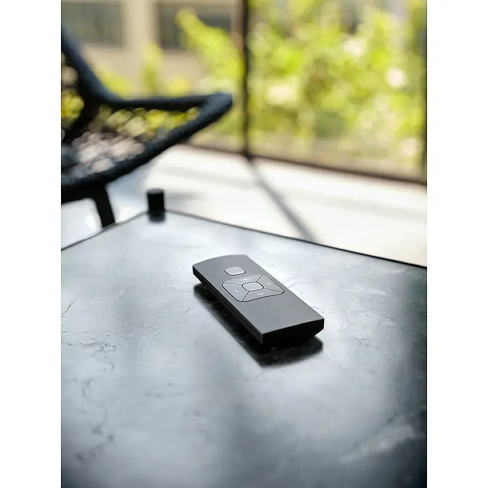 Funkhandsender MotionBlinds Smart Home Remote Control - 5 Kanäle - Eine elegante schwarze Fernbedienung liegt auf einem dunklen Tisch, perfekt für die moderne Inneneinrichtung und einfache Bedienung.