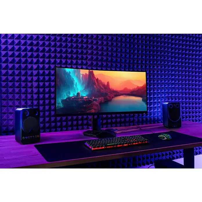 Noppenschaum Akupur - Pyramide, 100 x 50 x 4 cm, PU-Schaum - Produktaufnahme eines Gaming-Setups mit Monitor, Lautsprechern, Tastatur und Maus vor einer schallabsorbierenden Wand.