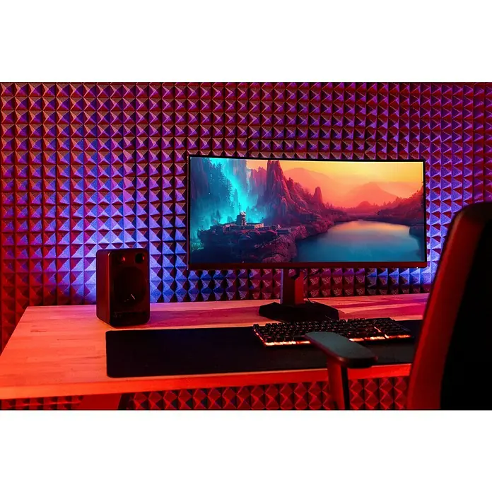 Noppenschaum Akupur - Pyramide, 100 x 50 x 4 cm, PU-Schaum - Gaming-Setup mit Monitor, Tastatur und Lautsprecher vor einer schallabsorbierenden Wand in atmosphärischer Beleuchtung.