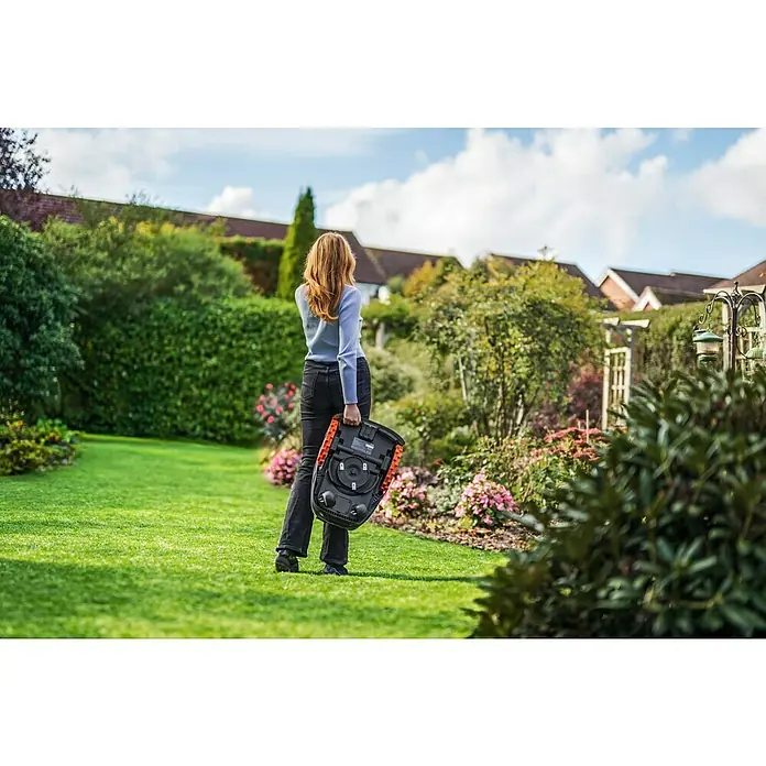 Segway Mähroboter Navimow i105E - 500 m², Schnittbreite: 18 cm, Satellitengestützte Navigation, RTK - Frau trägt einen Worx Landroid Mähroboter im Garten. Der Roboter hat eine schwarze Farbe mit orangefarbenen Details.