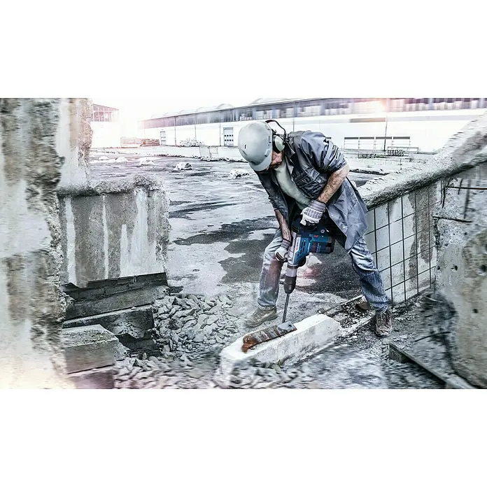Bosch Professional Kombihammer GBH 5-40 DCE - 1.150 W, 8,8 J, SDS-Max-Aufnahme - Ein Bauarbeiter mit einem Bosch-Bohrhammer bei Abrissarbeiten, ausgestattet mit Helm und Gehörschutz. Das Gerät ist blau und schwarz.