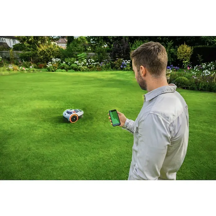 Segway Mähroboter Navimow i105E - 500 m², Schnittbreite: 18 cm, Satellitengestützte Navigation, RTK - Mann steuert einen Roboter-Rasenmäher mit seinem Smartphone im Garten. Der Rasen ist perfekt gepflegt und sattgrün.