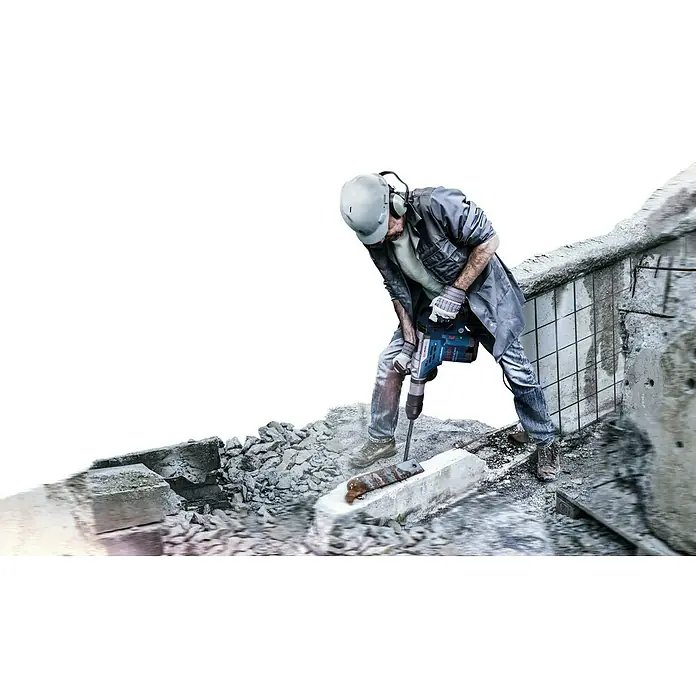 Bosch Professional Martillo combinado GBH5-40DCE - 1.150 W, 8,8 J, Alojamiento SDS-MAX - Un obrero de la construcción utiliza un martillo neumático Bosch para romper hormigón en una obra, equipado con protección.