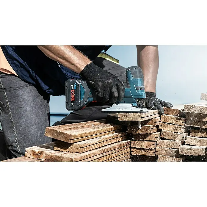Bosch Stichsägeblatt T144DHM - Abrasive Holzwerkstoffe, T-Schaft - Ein Bauarbeiter benutzt eine Bosch Akku-Stichsäge ProCORE 18V zum Zuschneiden von Holzlatten, während er Arbeitshandschuhe trägt.