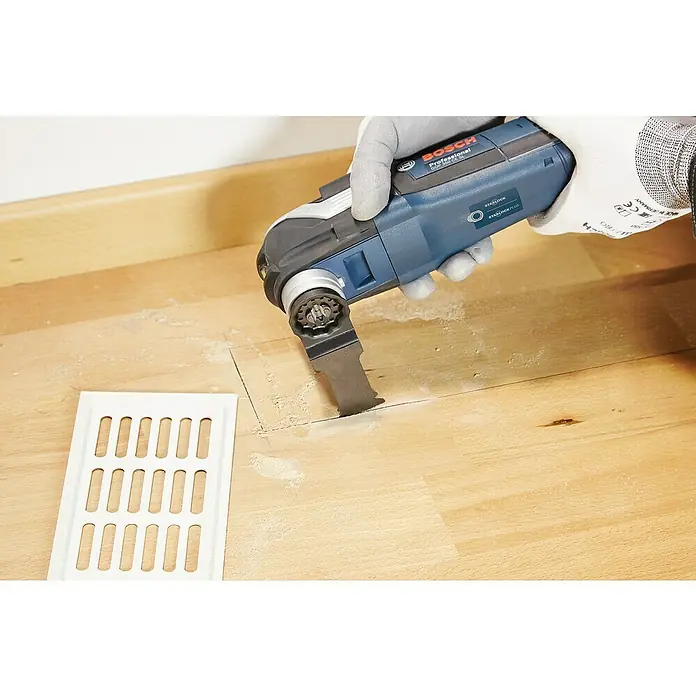 Bosch Installations-Set4 -tlg. - Ein Bosch Professional Multifunktionswerkzeug wird verwendet, um einen Schlitz in einem Holzboden neben einem weißen Lüftungsgitter zu schneiden.