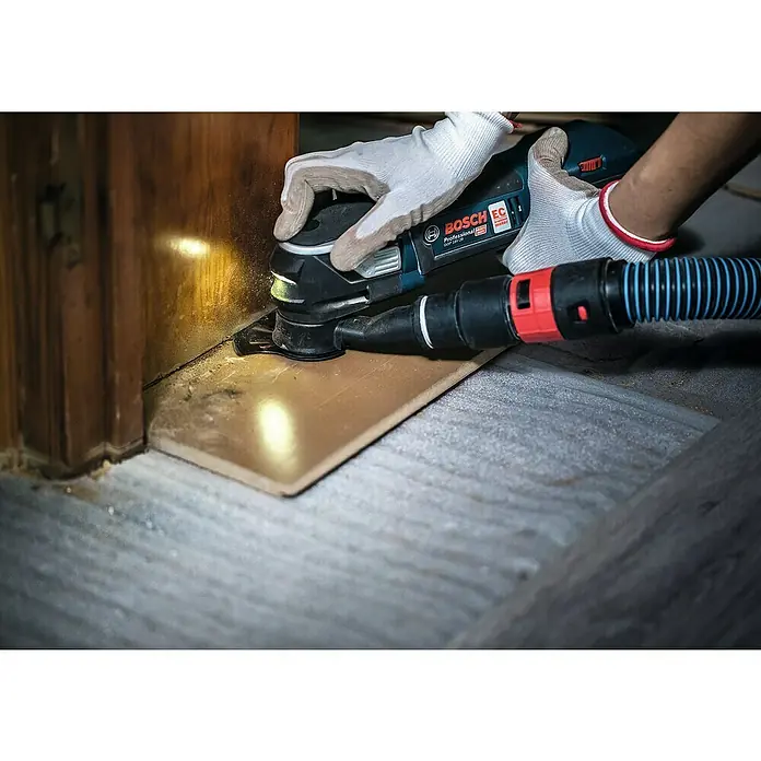 Bosch Segmentsägeblatt Multimaterial ACZ 105 ET - Durchmesser: 105 mm, Geeignet für: Holzwerkstoffe - Ein Bosch GOP 18V-28 Multifunktionswerkzeug im Einsatz beim Schneiden eines Holzstücks, mit angeschlossenem Staubsauger für saubere Arbeitsumgebung.