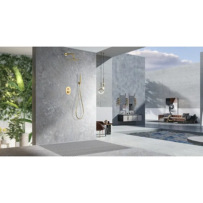 Imex Olimpo Sistema de ducha empotrado - Oro - Diseño de baño lujoso que muestra una ducha dorada y accesorios contra una pared de hormigón elegante, complementado con vegetación exuberante.