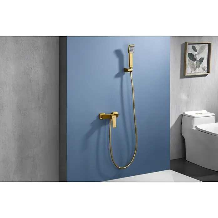 Imex Art Grifo monomando de ducha - Oro - Un elegante interior de baño con un grifo de ducha dorado montado en una pared pintada de azul, junto a un inodoro moderno y un elegante cuadro enmarcado.