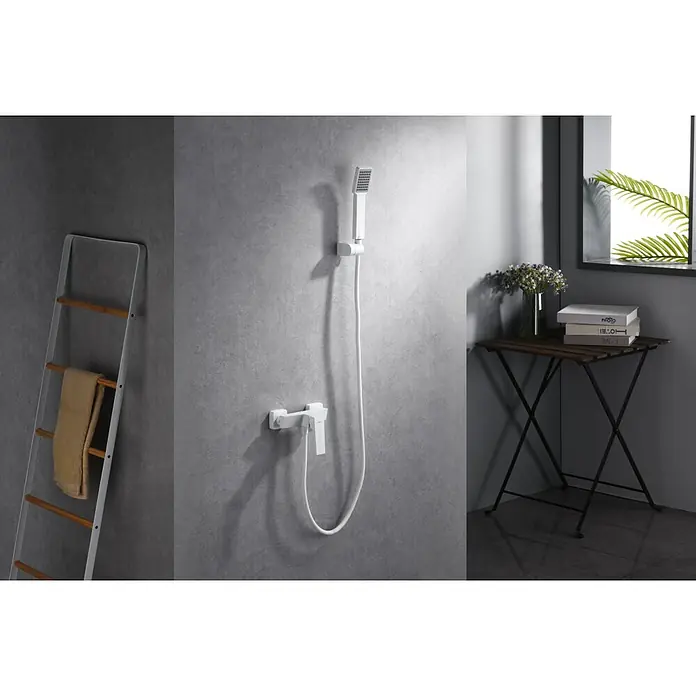Imex Art Grifo monomando de ducha - Blanco - Primer plano de un moderno grifo de ducha blanco contra una pared gris, complementado con una escalera de toallas y una mesa auxiliar.