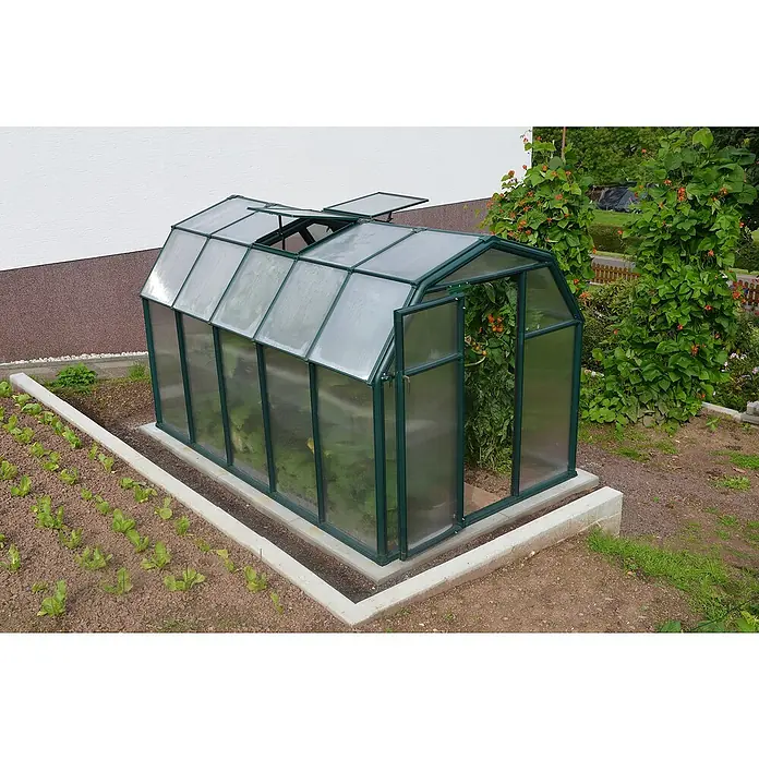 Palram – Canopia Invernadero Eco Grow - Medidas ext. (An x Pr): 204 x 321 cm, 6 mm, Verde - Primer plano de un invernadero con ventanas abiertas, rodeado de un jardín con plantas. El invernadero ofrece un espacio seguro.