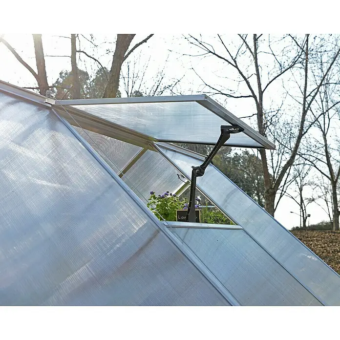 Palram – Canopia Ventana de techo Mythos - Cromo - Primer plano de una ventana de invernadero con plantas en el interior y un abridor automático de ventanas.