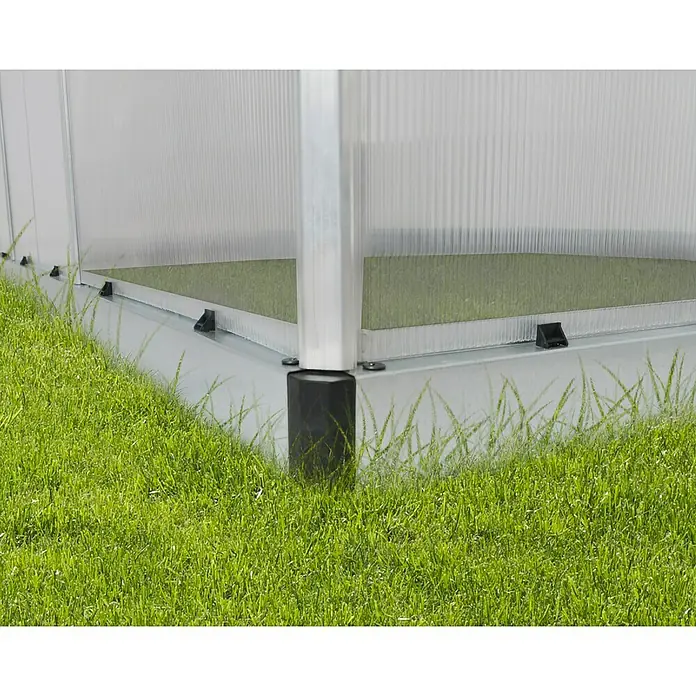 Palram – Canopia Invernadero Essence - Medidas ext. (An x Pr): 244 x 487 cm, Material de la pared lateral: Plástico, 6 mm, Plateado - Primer plano de una base de invernadero con marco plateado y base negra, rodeada de exuberante hierba verde.