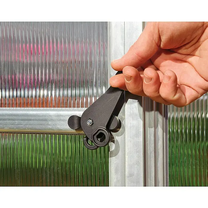 Palram – Canopia Invernadero Essence - Medidas ext. (An x Pr): 244 x 487 cm, Material de la pared lateral: Plástico, 6 mm, Plateado - Primer plano de un cerrojo de puerta negro en una puerta transparente, con una mano operándolo.