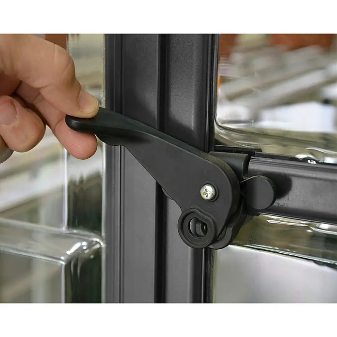 Palram – Canopia Invernadero Balance - Medidas ext. (An x Pr): 244 x 247 cm, 0,7 mm, Gris - Una mano opera una manija de ventana de plástico negro, fijada a un marco de ventana.