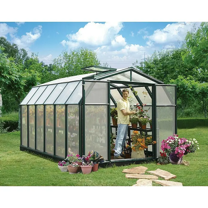 Palram – Canopia Invernadero Hobby Gardener - Medidas ext. (An x Pr): 266 x 391 cm, 6 mm, Verde - Un invernadero con una persona dentro, rodeado de plantas y flores.