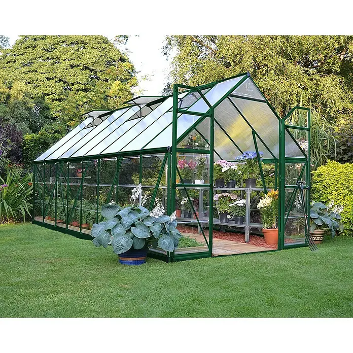 Palram – Canopia Invernadero Balance - Medidas ext. (An x Pr): 244 x 487 cm, 0,7 mm, Verde - Esta imagen muestra un invernadero de vidrio y estructura verde, rodeado de césped y exuberante vegetación.