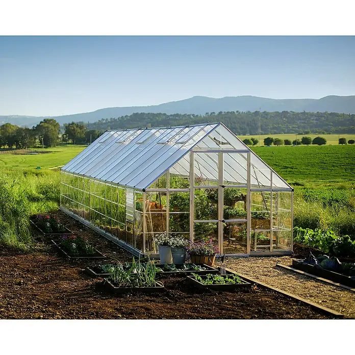 Palram – Canopia Invernadero Balance - Medidas ext. (An x Pr): 304 x 844 cm, 0,7 mm, Plateado - Invernadero luminoso con plantas en un campo. El invernadero alberga una variedad de plantas en macetas y recipientes.
