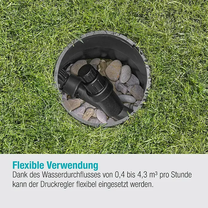 Gardena Sprinklersystem Druckminderer - 1″ - Das Bild zeigt einen Druckregler in einem schwarzen Gehäuse, eingebettet in Gras und Steine.