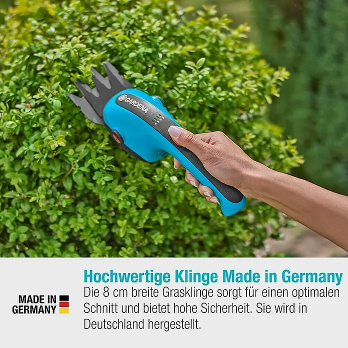 Gardena ClassicCut Akku-Grasschere Li - 3,6 V, 1 Akku, Schwertbreite: 8 cm - Nahaufnahme einer GARDENA Akku-Grasschere, die einen grünen Busch schneidet, mit dem Hinweis "Hergestellt in Deutschland".