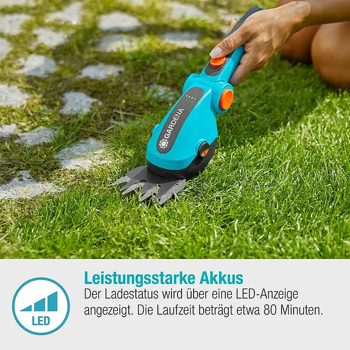 Gardena ComfortCut Akku-Gras- & Strauchschere Li - 3,6 V, Li-Ionen, 1 Akku, Schwertbreite: 8 cm - Das Bild zeigt eine Gardena Akku-Grasschere im Einsatz. Die Schere ist blau-schwarz mit orangefarbenen Akzenten und schneidet Gras an einem Rasenrand.
