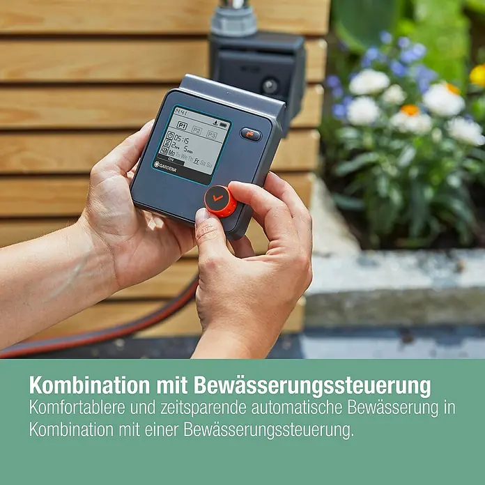 Gardena Micro-Drip Bewässerungs-Set Hochbeet/Beet Start-Set - 35 -tlg., Geeignet für: Reihenbewässerung, 35 Pflanzen - Nahaufnahme einer Person, die eine Gardena Bewässerungssteuerung bedient, die an einer Holzwand befestigt ist.