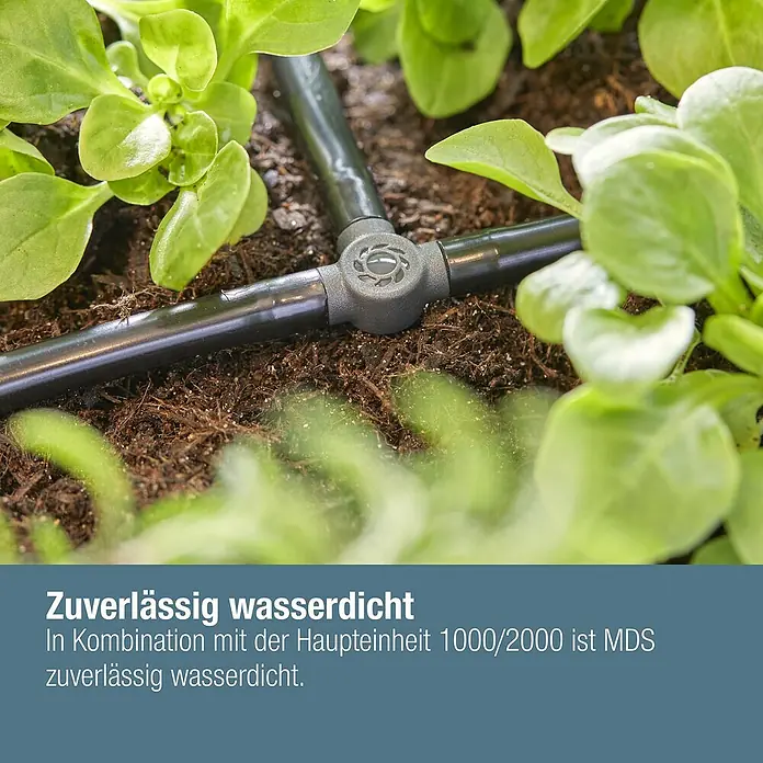 Gardena Micro-Drip T-Stück - 3/16" x 4,6 mm, 10 Stk. - Nahaufnahme eines T-Stücks eines Bewässerungssystems zwischen Pflanzen.