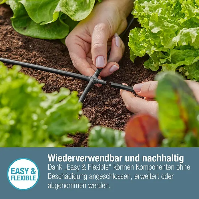 Gardena Micro-Drip Kreuzstück - 3/16" x 4,6 mm, 10 Stk. - Nahaufnahme einer Person, die ein Bewässerungssystem mit T-Stück in einem Gartenbeet installiert.