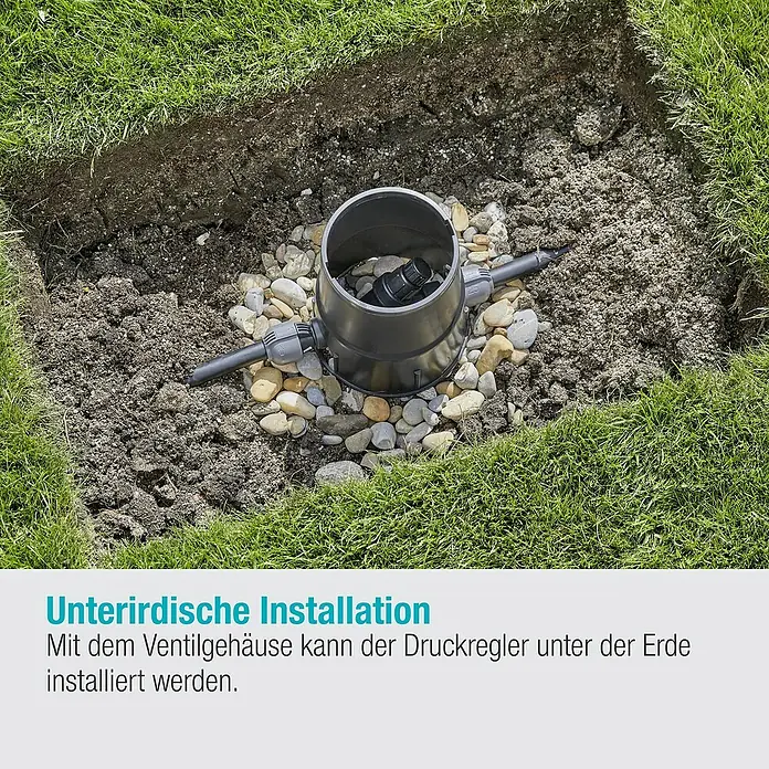 Gardena Sprinklersystem Druckminderer - 1″ - Erdverlegte Installation eines schwarzen Ventilgehäuses auf Steinen im Garten.