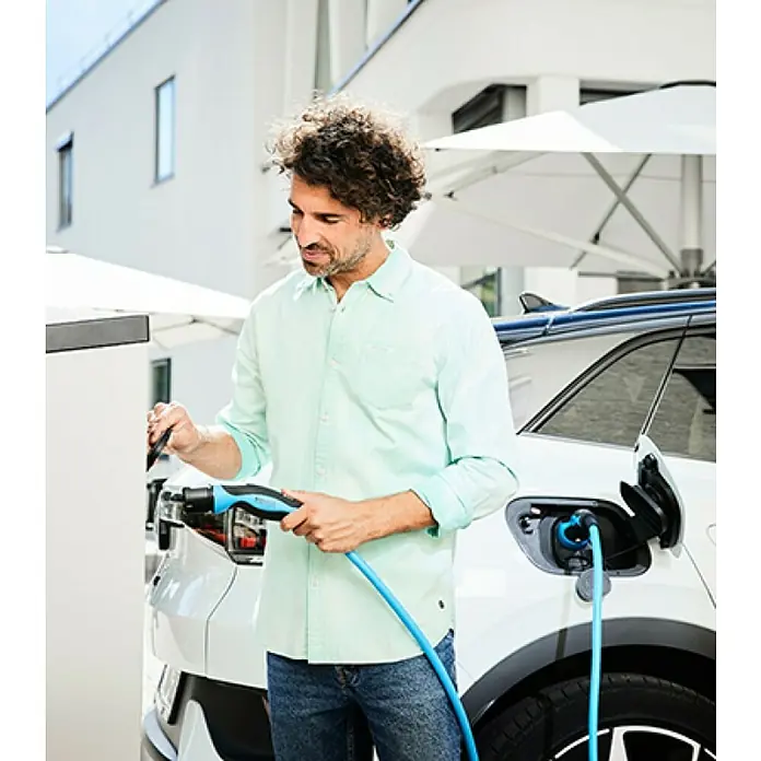 Mennekes Kfz-Ladekabel Mode 3 Typ 2 für Elektrofahrzeuge - Nennstrom: 32 A, Kabellänge: 7,5 m - Ein Mann schließt sein Elektroauto mit einem blauen Kabel an einer Ladestation an, um es aufzuladen.