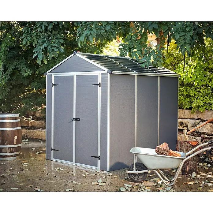 Palram – Canopia Gartenhaus Rubicon - Außenmaß inkl. Dachüberstand (B x T): 1,85 x 3,78 m, Kunststoff, Grau - Ein graues Gartenhaus aus Kunststoff steht im Freien, umgeben von Grün. Es bietet Stauraum und Schutz für Gartengeräte und Zubehör.