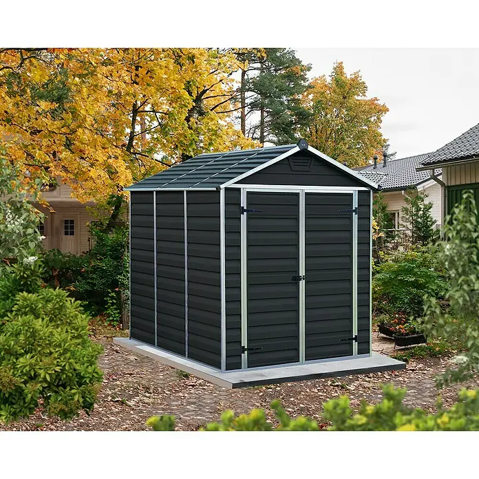 Palram – Canopia Caseta de jardín Skylight - Medidas ext. (An x Pr): 185 x 229 cm, Plástico, Antracita - Cobertizo de jardín gris oscuro con detalles plateados en un entorno natural al aire libre. El cobertizo tiene una puerta doble y se apoya en una base.